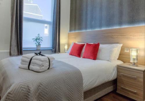 a bedroom with a large bed with red pillows at The Bromley's in Great Yarmouth