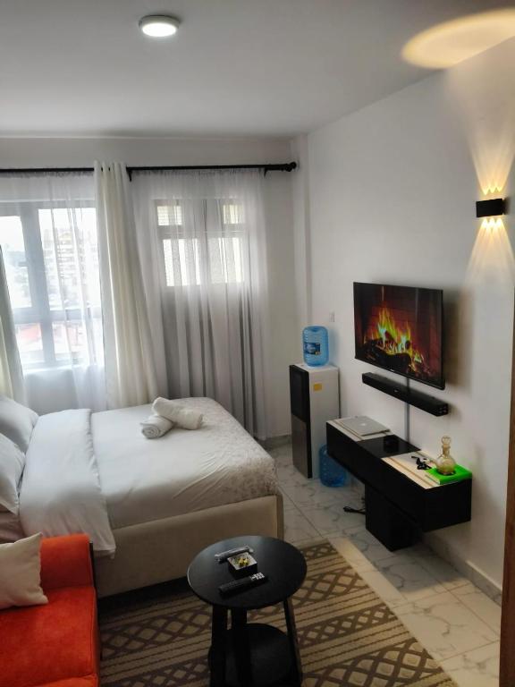 une chambre avec un lit et une télévision sur un mur dans l'établissement Naivera, à Nairobi