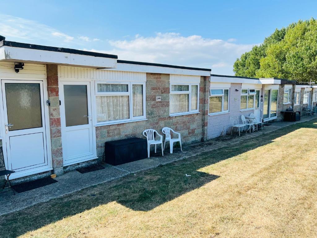 eine Reihe weißer Stühle vor einem Gebäude in der Unterkunft 2 Bedroom Chalet SB144, Sandown Bay, Isle of Wight, Dog Friendly, Free Wifi in Brading