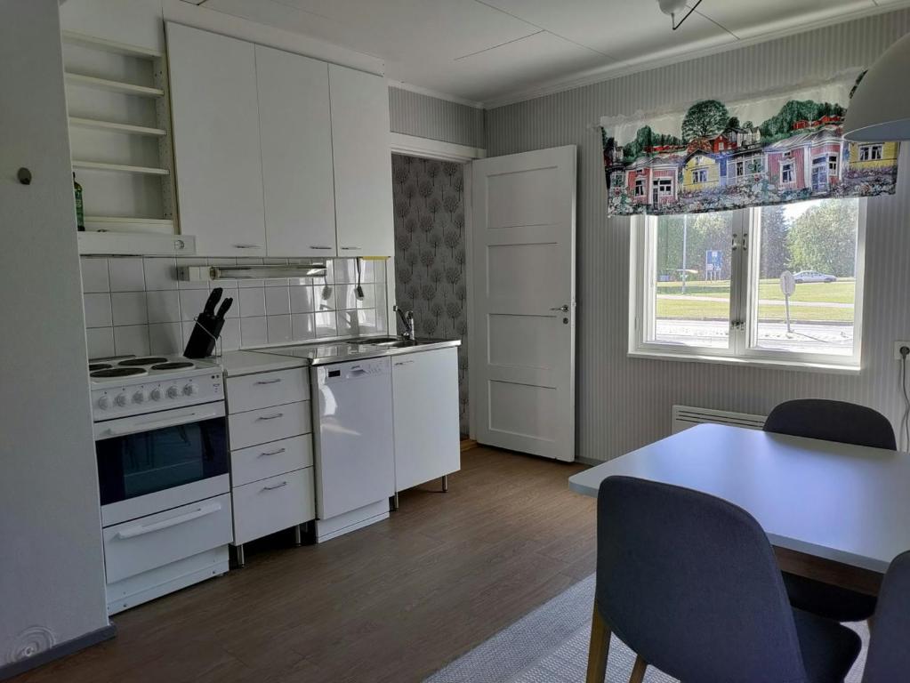 a kitchen with white cabinets and a table and a dining room at Central Apartment for 4 in Kemi