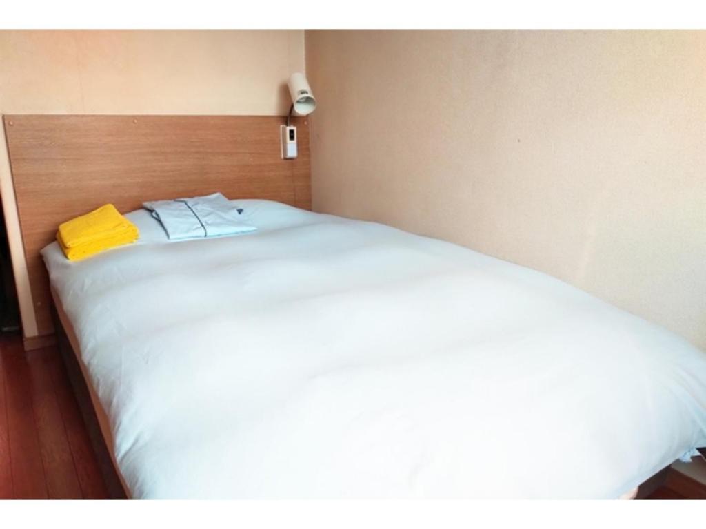 ein großes weißes Bett mit einem gelben Handtuch darauf in der Unterkunft Hotel Park Light - Vacation STAY 39467v in Inai