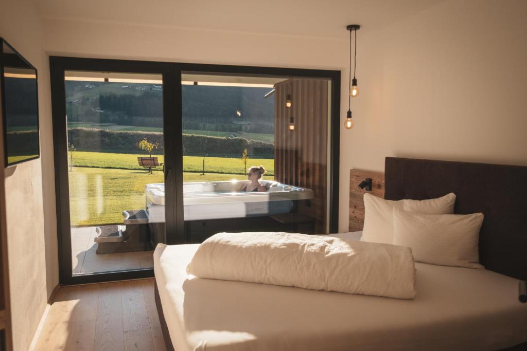 a bedroom with a bed and a tub with a person in it at Sottla - your mountain home in Valdaora