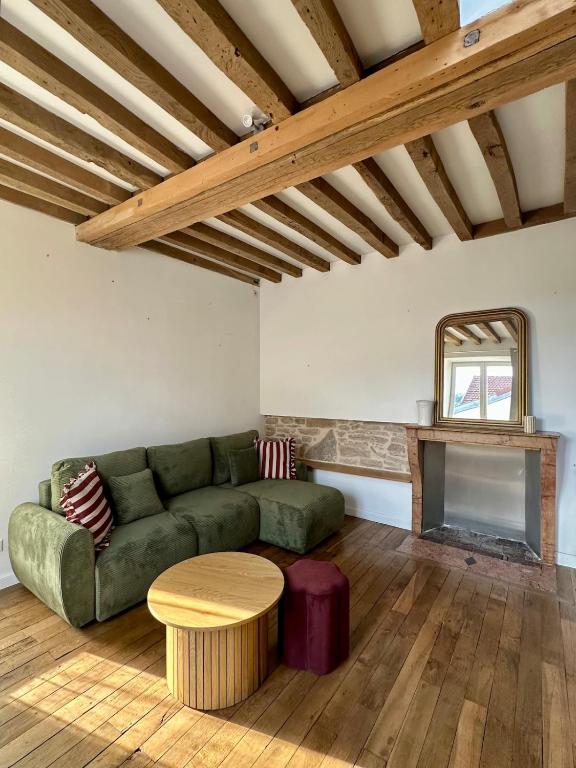 a living room with a green couch and a table at Maison cosy à côté de Beaune in Savigny-lès-Beaune