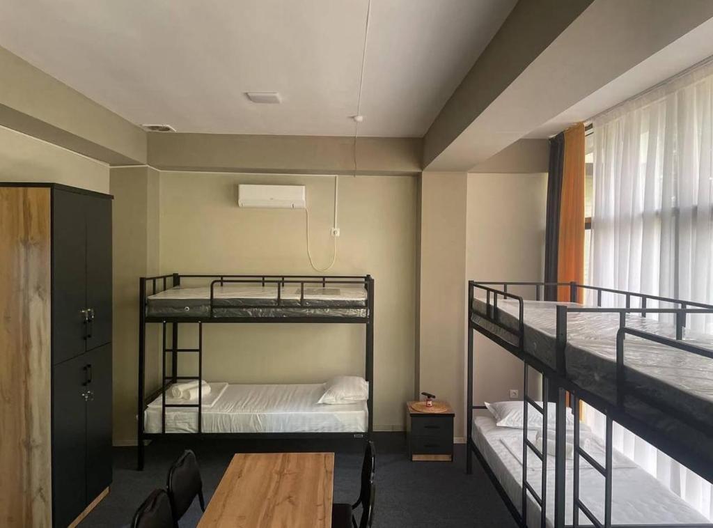 a dorm room with two bunk beds and a table at Nari Hotel in Tashkent