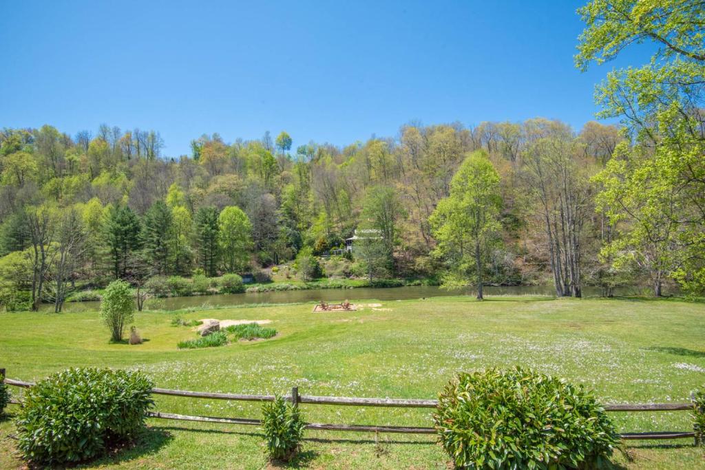 a large grassy field with a fence and trees at 1 Bedroom Cabin Overlooking New River-- Sleeps 4, Dogs OK, Fire Pit & More in Glendale Springs