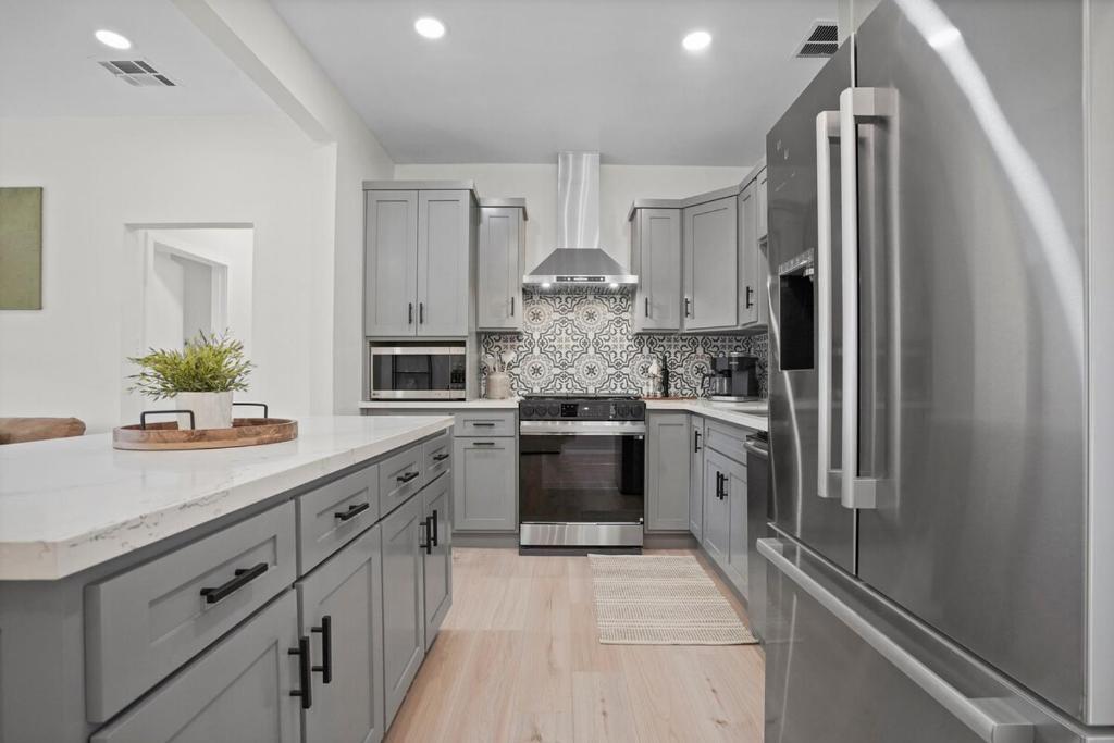 a kitchen with white cabinets and a stainless steel refrigerator at Stylish Cozy getaway in West Valley Area Heliport