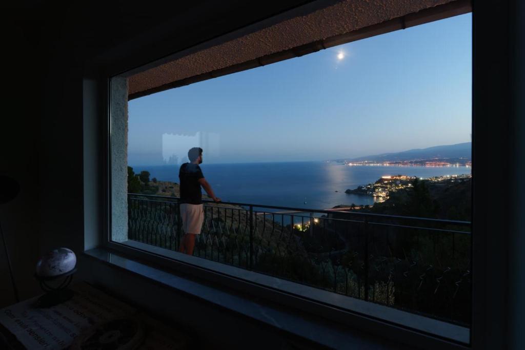 a man standing on a balcony looking at the ocean at Maison Stalettì - Sea View Suite in Copanello