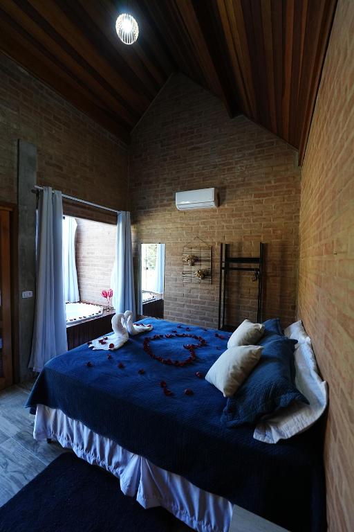 a bedroom with a large bed with blue sheets and pillows at Chalé Petra - Recanto da Pedra in São Bento do Sapucaí
