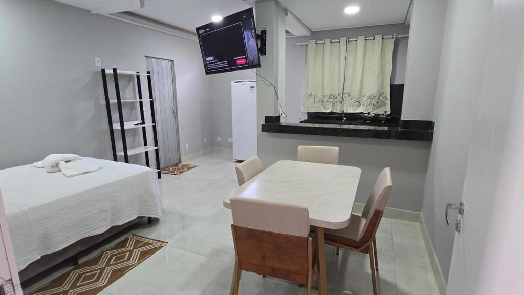 a room with a table and a white table and a tv at Suite Harmonia in Alto Paraíso de Goiás