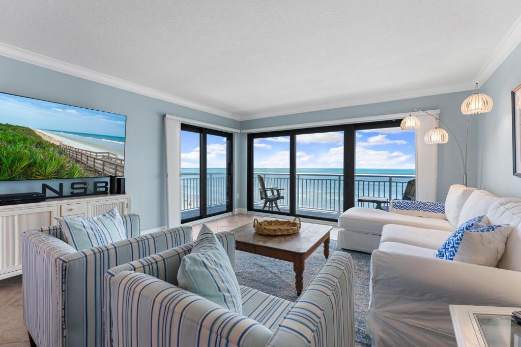 a living room with couches and a view of the ocean at Updated direct oceanfront corner with a wrap-around balcony, heated pool and beach access in Bottle Island