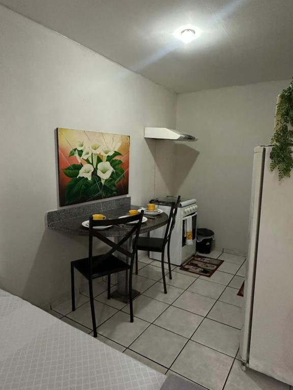 a kitchen with two chairs and a table and a painting at Hotel Paradão Linhares in Linhares