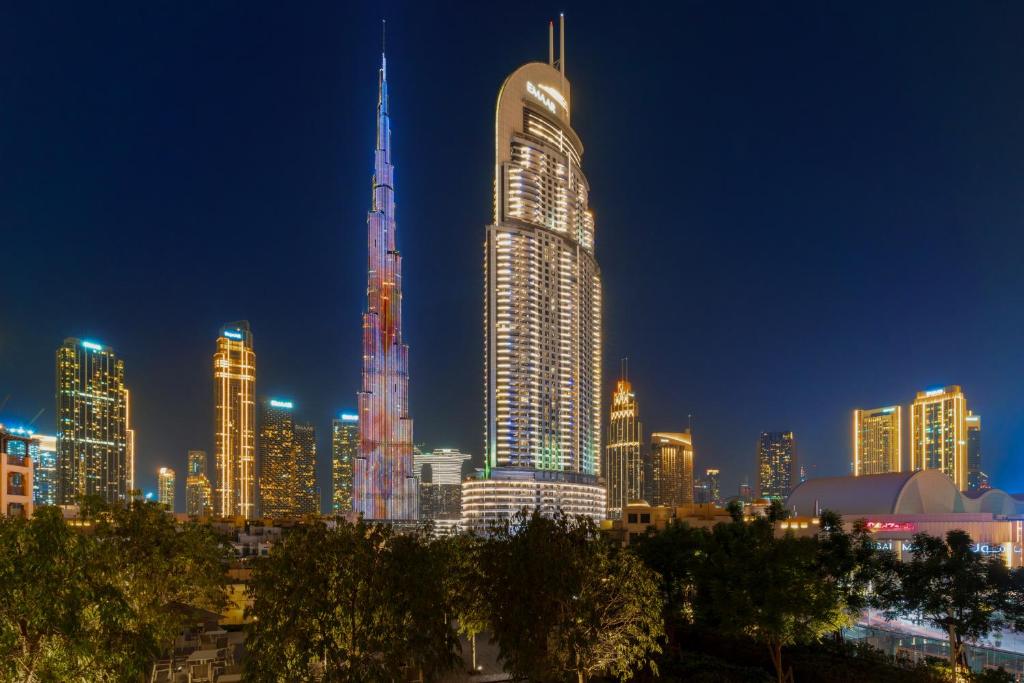 een skyline van de stad 's nachts met een hoog gebouw bij Luxury 2BR with Burj Khalifa Views l Near Dubai Mall in Dubai