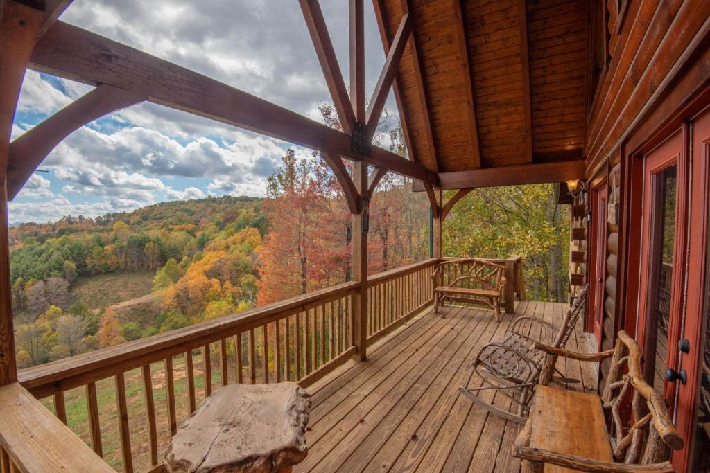 a porch of a cabin with a swing at 7 Bd Log Cabin Retreat- Game Rm, Hot Tub, Room for the Whole Family! in Grassy Creek
