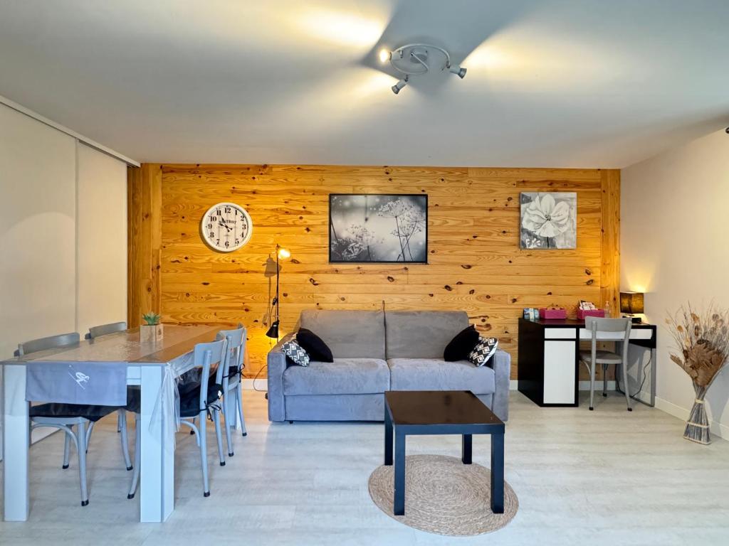 una sala de estar con un sofá y una mesa en T2 ensoleillé. Terrasse, jardin commun, vue, parking., en Cauterets