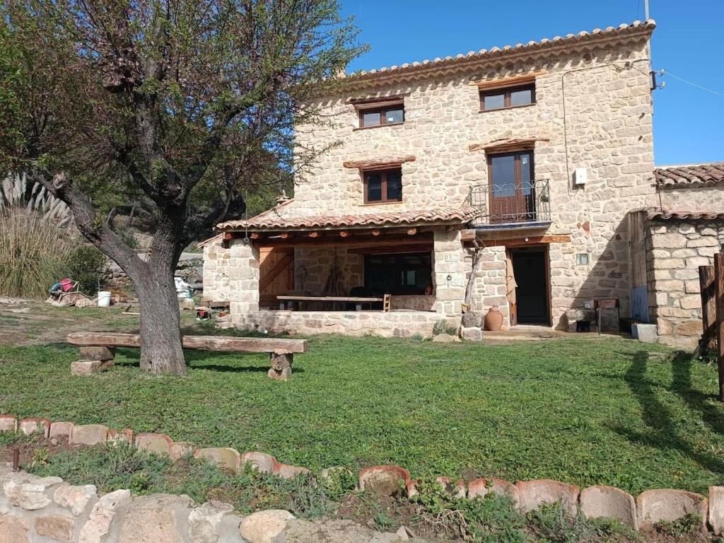 a stone house with a tree and a bench at El Masico Rural in Olba