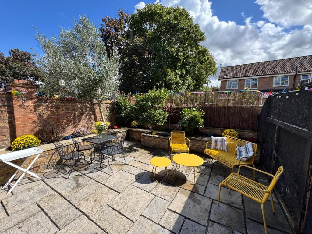 a patio with tables and chairs in a backyard at Willow Tree Retreat Airport Friendly 3BR House, with Garden & Office in Northolt