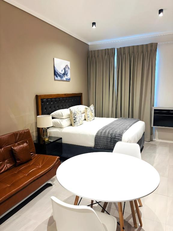 a hotel room with a bed and a table and a couch at Menlyn Maine Residences in Pretoria