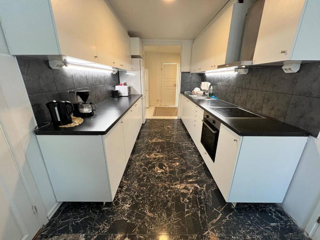 a kitchen with white cabinets and black counter tops at 5 beds apartment in Västerås