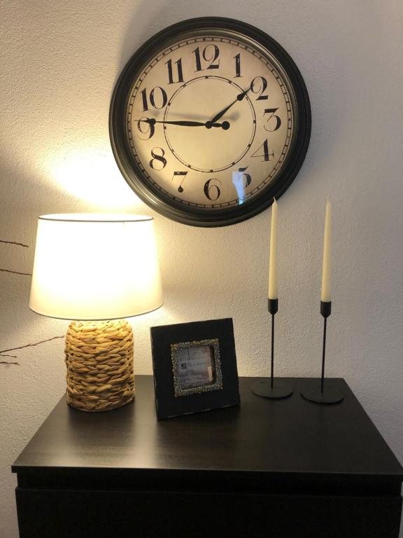 un orologio su una parete sopra un tavolo con due candele di ZMC Apartment a Orăştie
