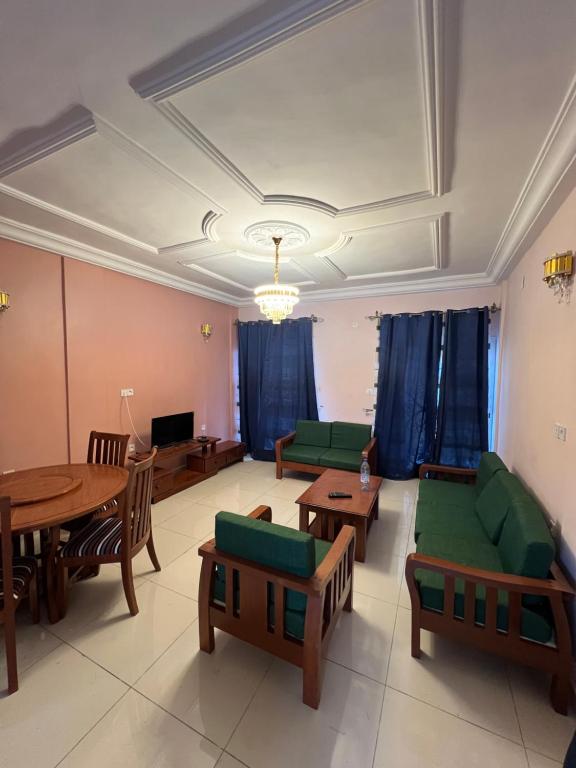 a living room with couches and tables and a tv at La ESPERANZA in Kribi