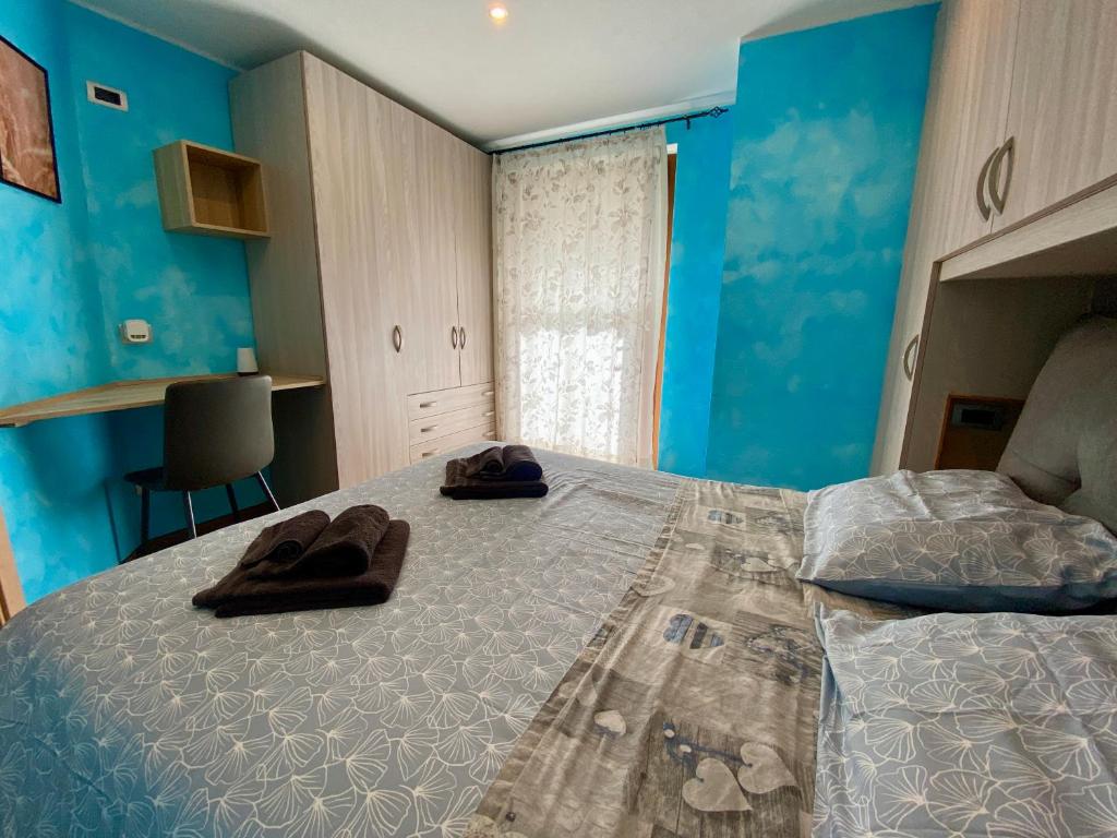 a bedroom with blue walls and a bed with slippers on it at Appartamento Serenella in Valdidentro