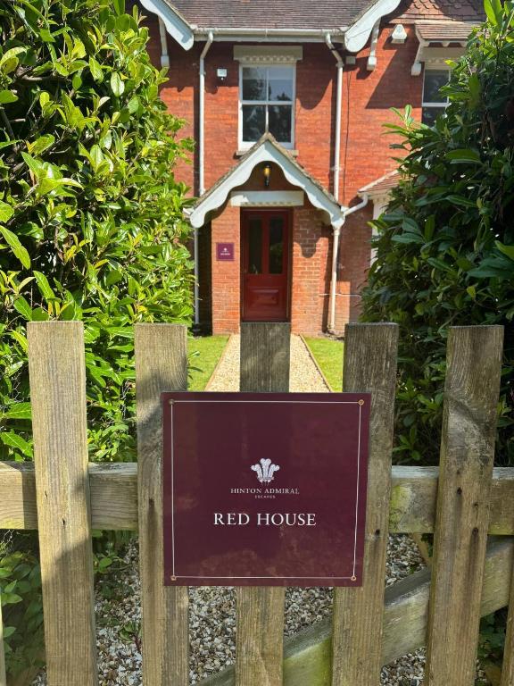 a sign on a wooden fence in front of a red house at Red House in Hinton