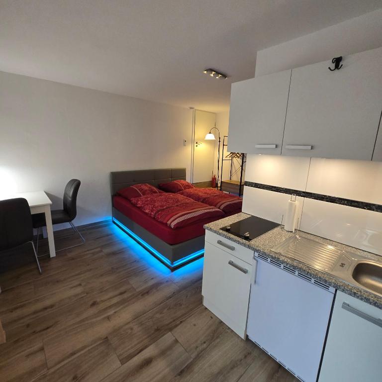 a room with a bed with a red blanket and a table at Gemütliches und komfortables Studio in Frankfurt in Frankfurt