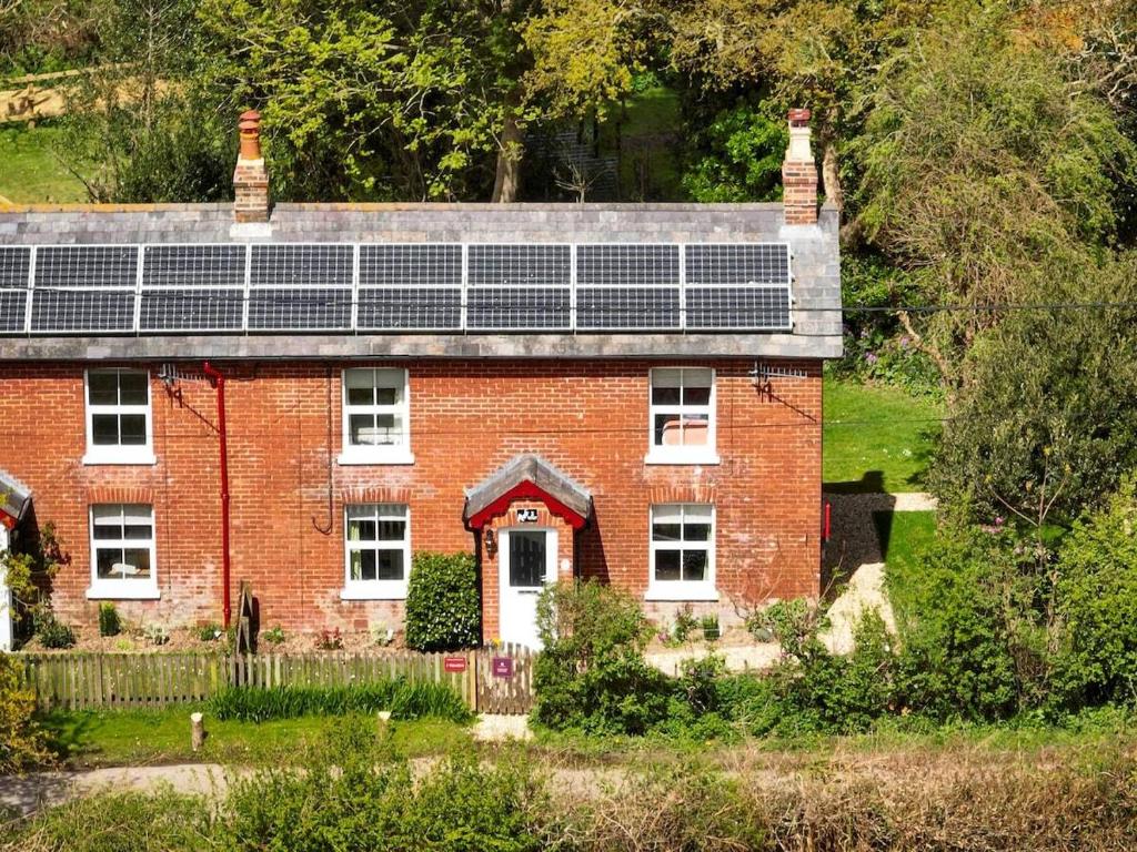 a red brick house with solar panels on it at Foxglove Cottage in Bransgore