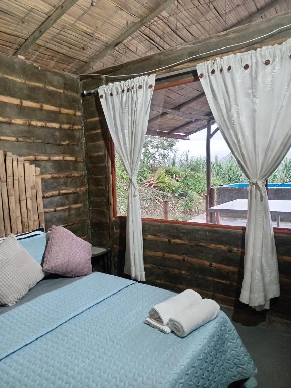 a bedroom with a bed and a window with curtains at Posada Rural Aguita de Panela in La Vega