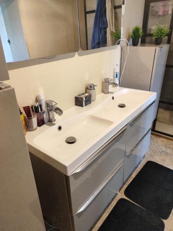 Un baño con un lavabo blanco y un espejo. en Chambre a 5 min de Center Parc bois aux daims, en Les-Trois-Moutiers