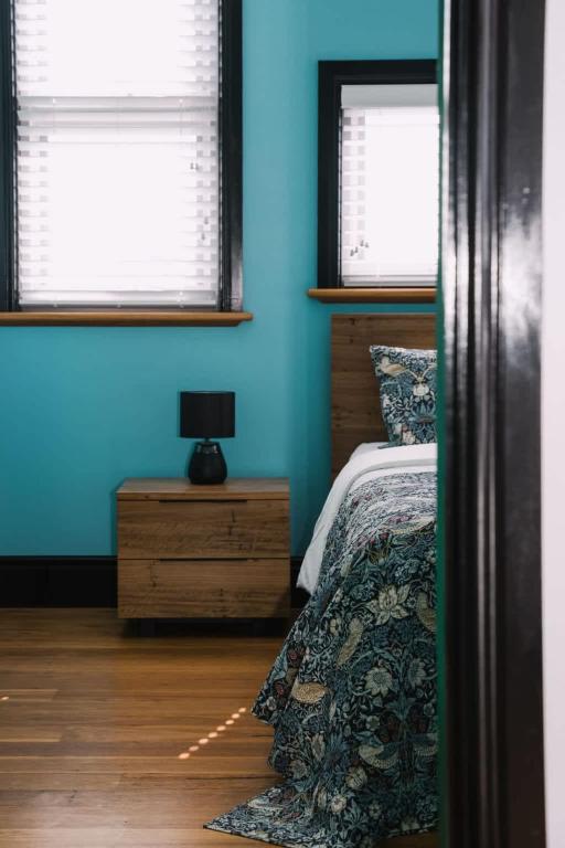 a blue bedroom with a bed and two windows at Saltwood Peterborough in Peterborough