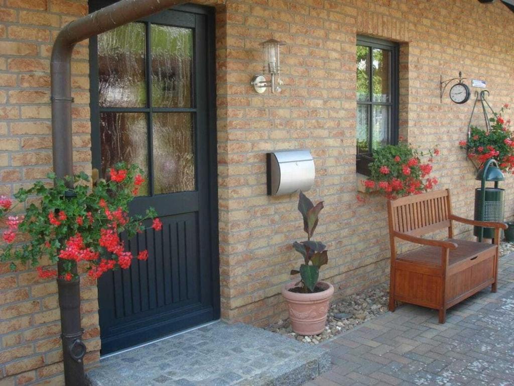 una puerta de una casa con un banco y flores en Holiday home in Waren with swimming pool, en Waren