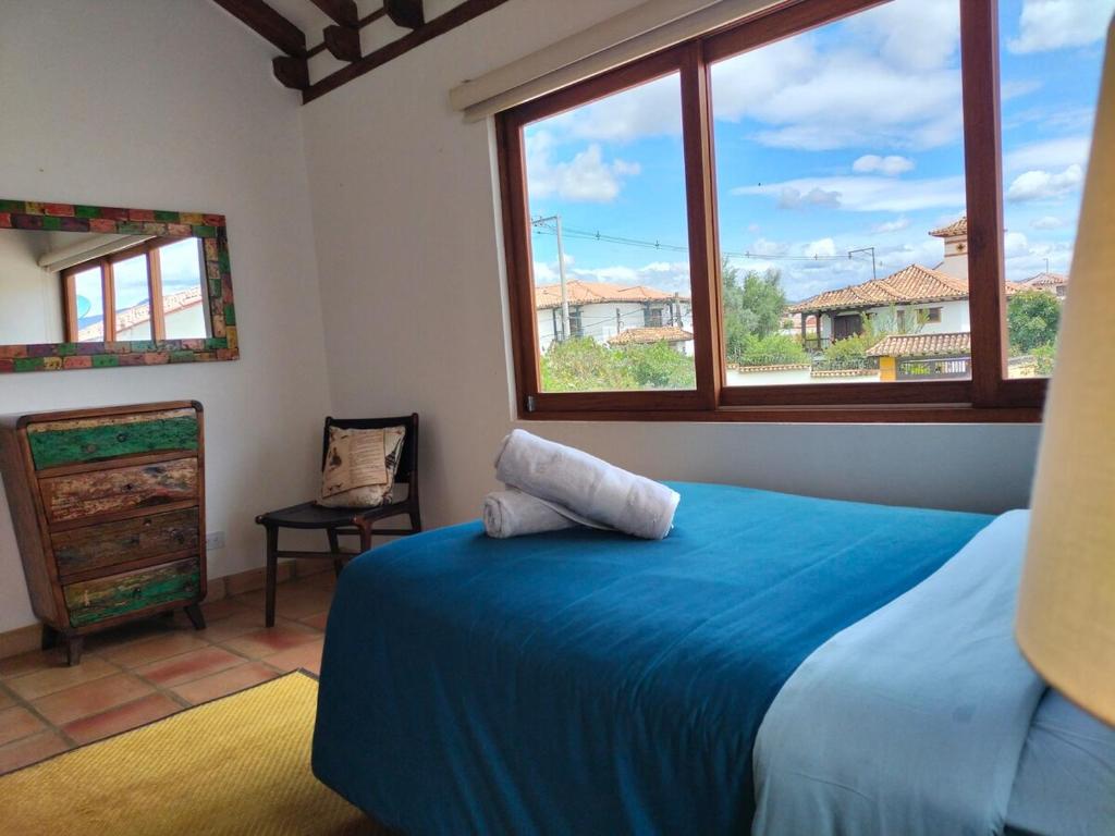 Un dormitorio con una cama azul y dos ventanas. en Exclusiva Casa BBQ Parking & Confort, en Villa de Leyva