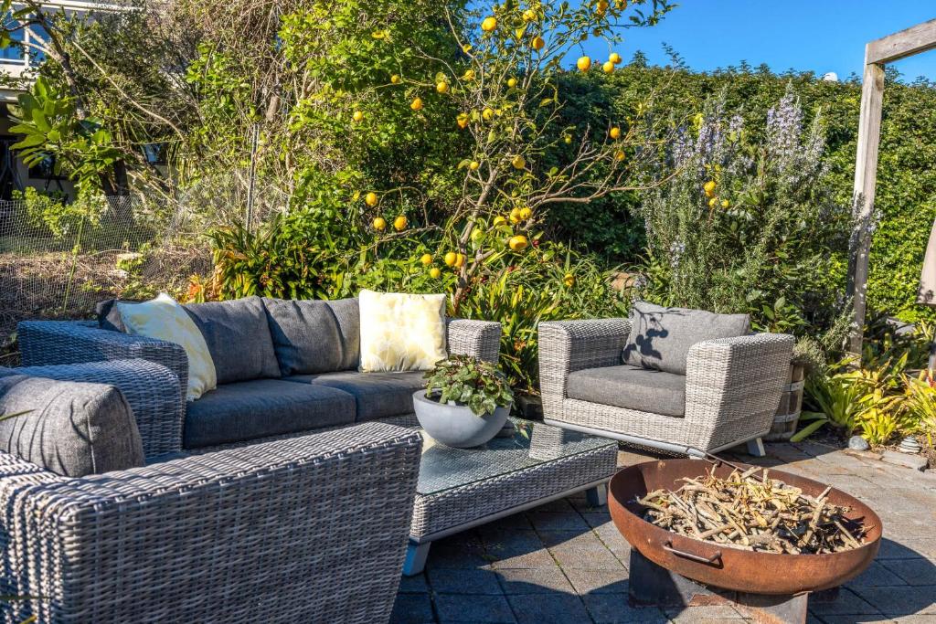 a patio with a couch and chairs and an orange tree at Waiheke Oasis - Your Summer Sanctuary in Waiheke Island
