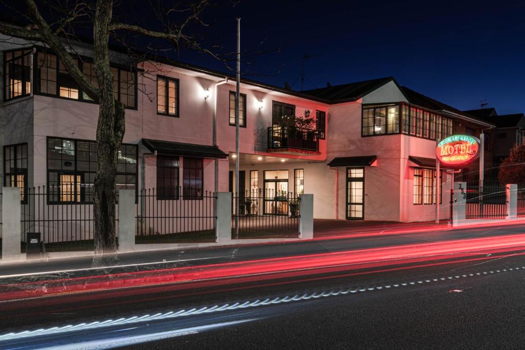a pink building with a neon sign on a street at Greenlane Manor Motel in Auckland