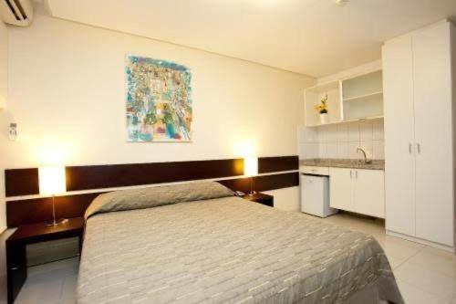 a bedroom with a large bed and a kitchen at Flat 502 América Tower, ao lado do Salvador Shopping in Salvador