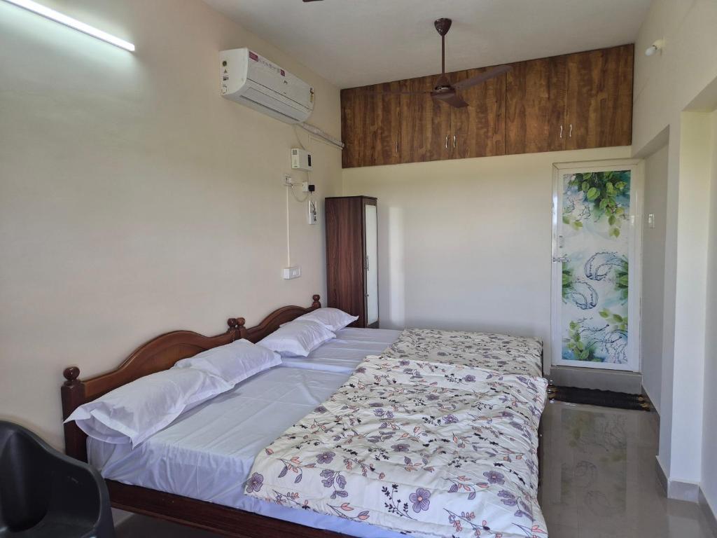 a bedroom with two beds and a fan at STM StayInn in Nāttarasankottai