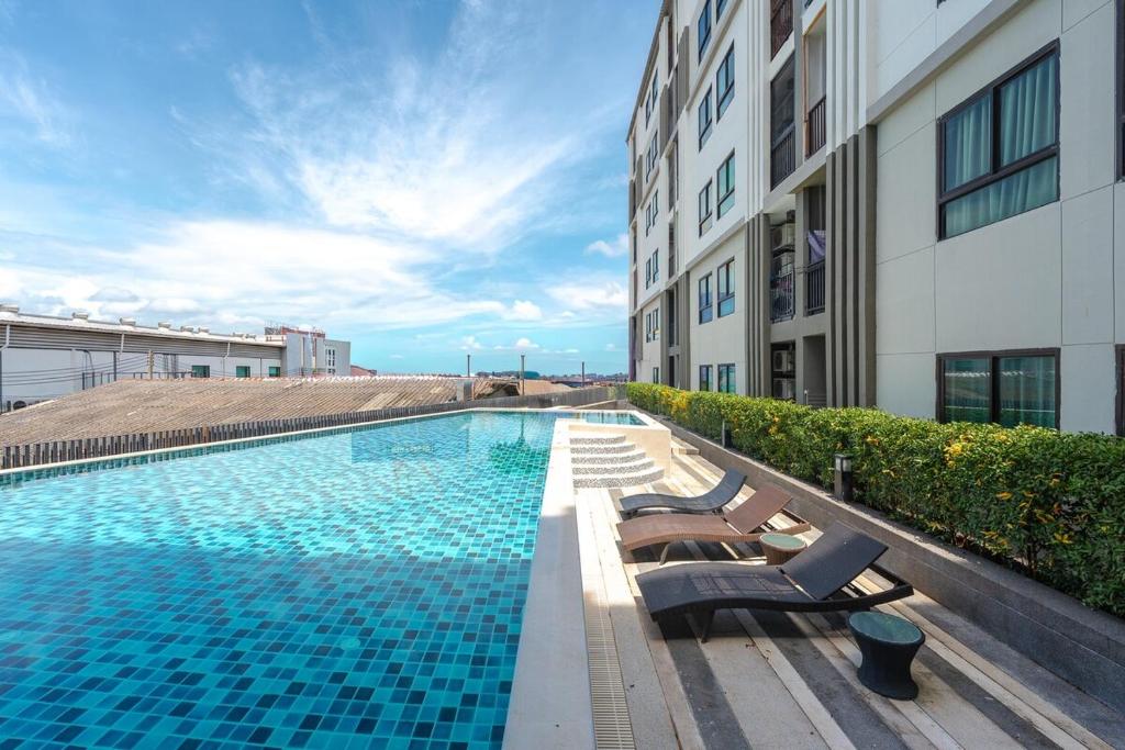 a swimming pool with lounge chairs next to a building at C237 Brand New 1BR Condo Pool Gym Near Beach in Ban Thalat Choeng Thale