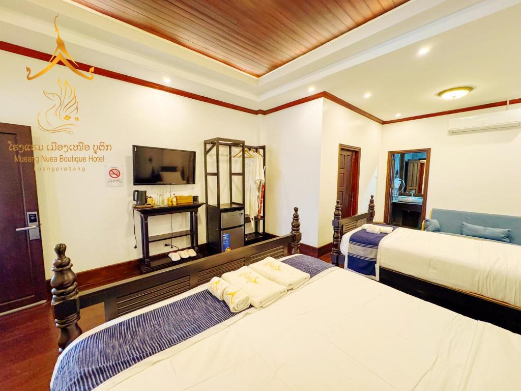 a hotel room with two beds and a television at Mueang Nuea Boutique Hotel in Luang Prabang