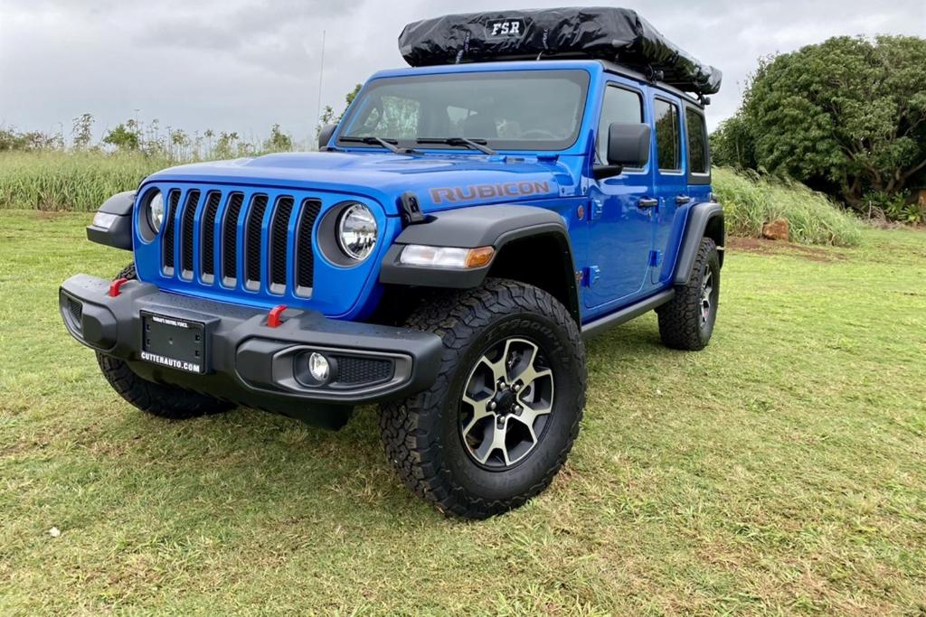 a blue jeep parked in a field at Island Getaway Camper Cozy Rooftop Tent & Full Gear Kauai in Anahola
