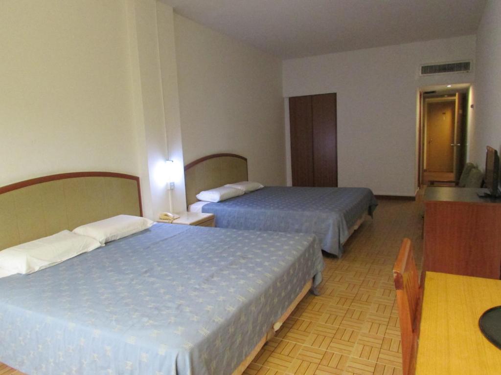ein Hotelzimmer mit 2 Betten und einem TV in der Unterkunft Hotel Supreme in Singapur