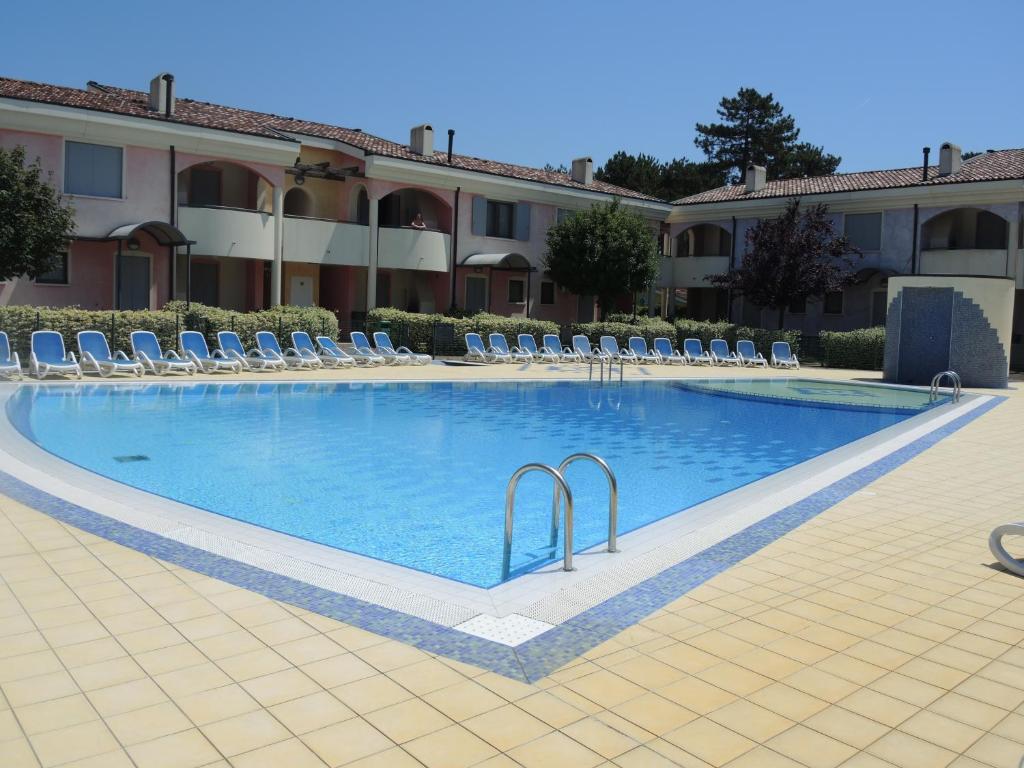 una gran piscina con sillas y un edificio en Villaggio Tulipano, en Bibione