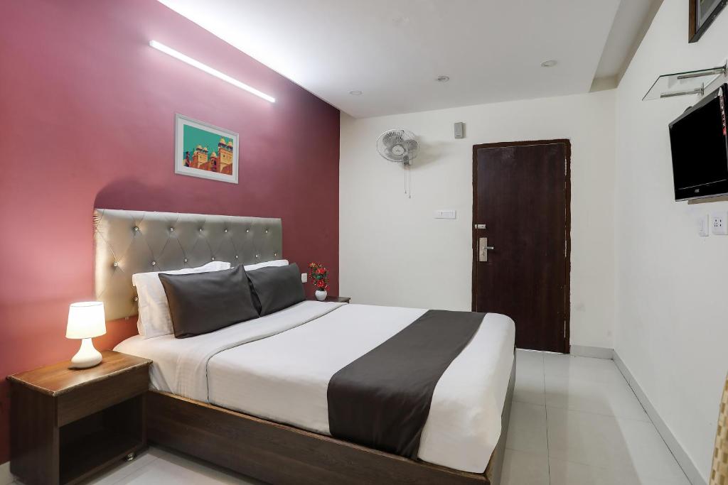 a bedroom with a bed and a red wall at Super Collection O Lotus Grand in Hyderabad
