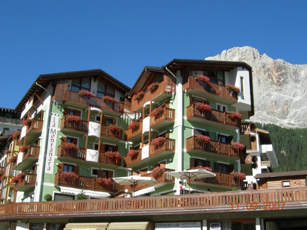 un bâtiment dans les montagnes avec des fleurs sur les balcons dans l'établissement B&B La Montanara, à San Martino di Castrozza