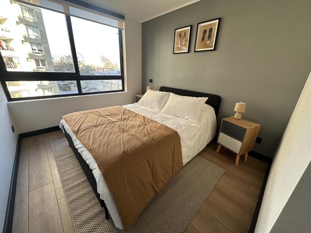 ein kleines Schlafzimmer mit einem Bett und einem Fenster in der Unterkunft Oceana Suites San Eugenio, Ñuñoa in Santiago