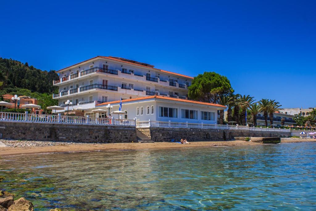 a building on the beach next to the water at Chryssi Akti Hotel in Argasi