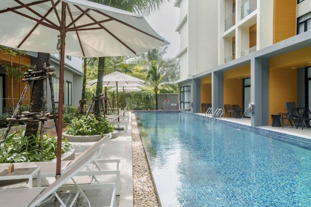 a swimming pool with chairs and an umbrella next to a building at Wyndham Gardens Elegant Studio Forrest View 2228 in Nai Thon Beach
