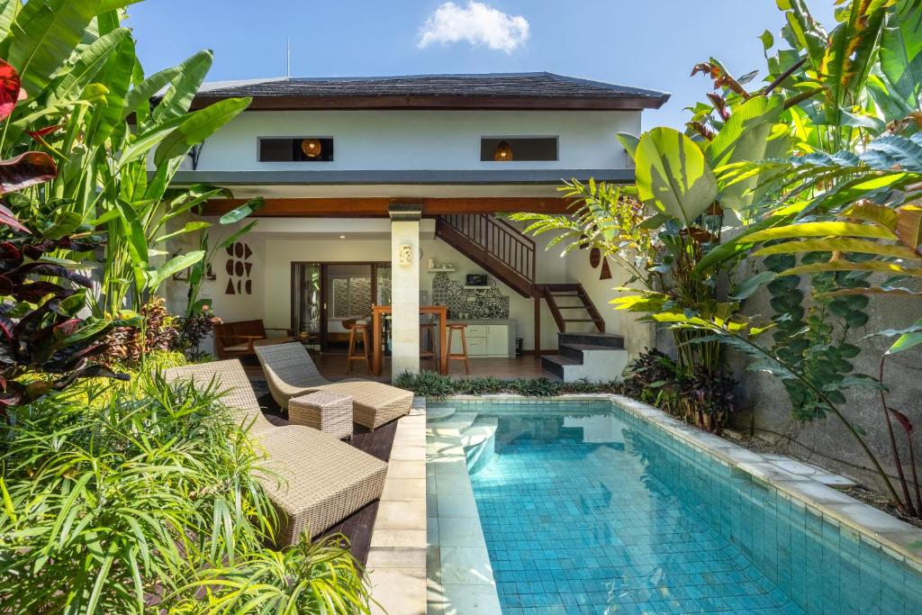 a villa with a swimming pool and a house at Cove Belle Asana in Canggu