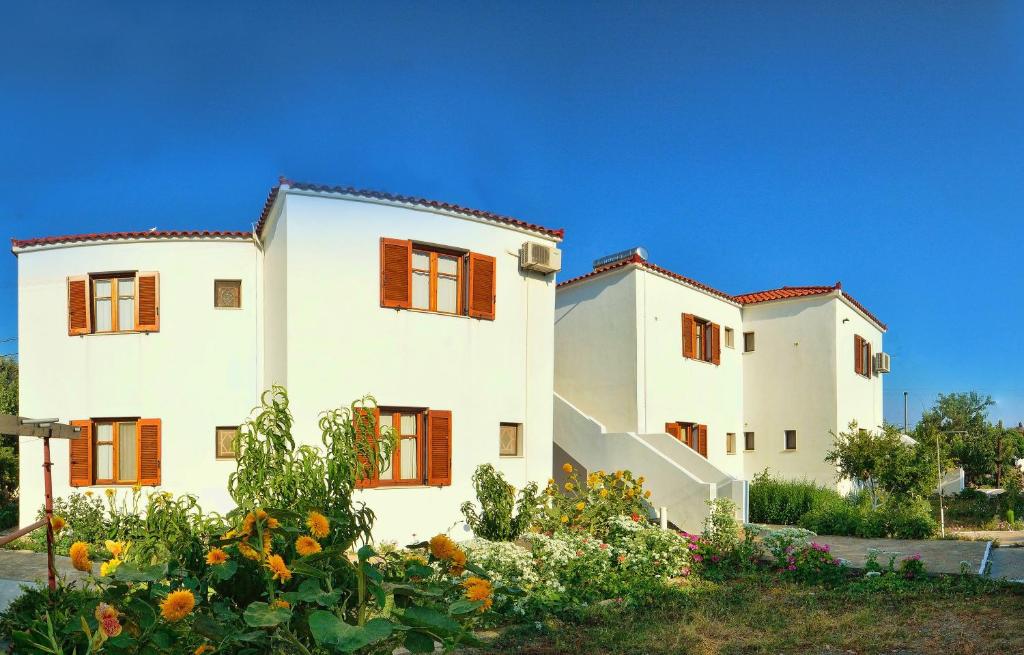 a large white building with red windows and flowers at Studios Calvinos in Marathokampos