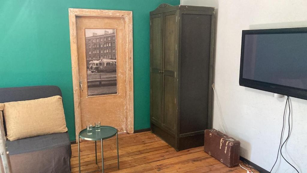 a living room with a couch and a tv and a cabinet at Barinu Street Apartment in Liepāja